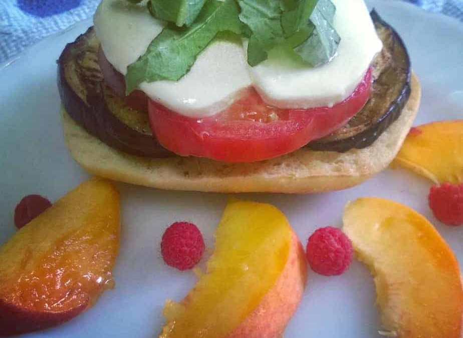 Open faced eggplant sandwich topped with tomato, fresh mozzarella is topped with some basil!